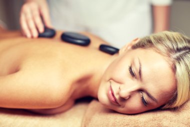 close up of woman having hot stone massage in spa clipart