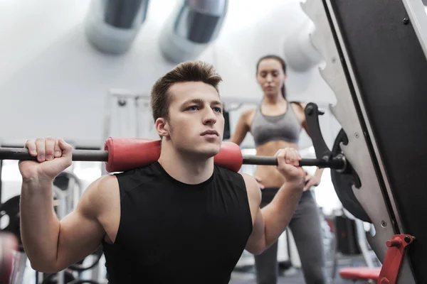 Homem e mulher com músculos de flexão barbell no ginásio — Fotografia de Stock