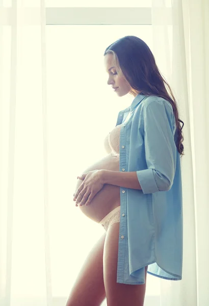 Счастливая беременная женщина с большим голом животом дома — стоковое фото