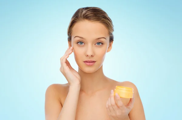 Mujer joven aplicando crema en su cara —  Fotos de Stock