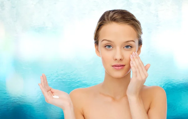 Young woman applying cream to her face — Stock Photo, Image