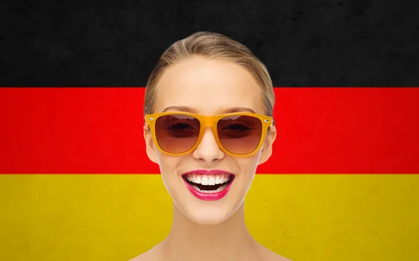 Happy young woman in sunglasses over german flag — Stok fotoğraf