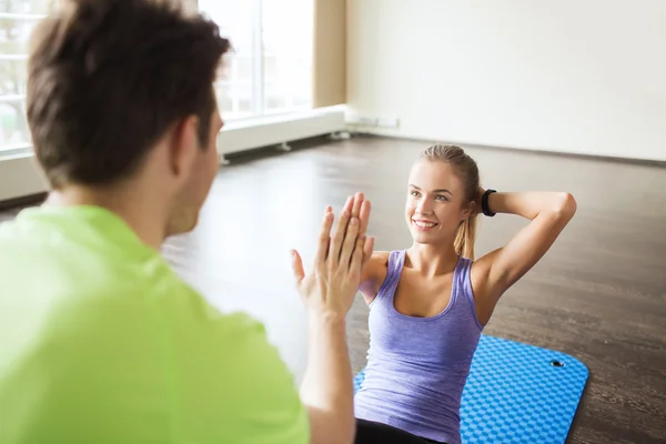 Vrouw met personal trainer doen sit ups in gym — Stockfoto