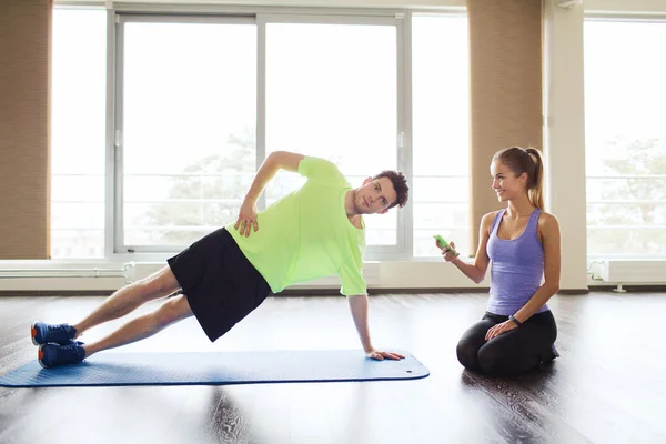 Мужчина и женщина делают упражнения на доске на коврике в спортзале — стоковое фото