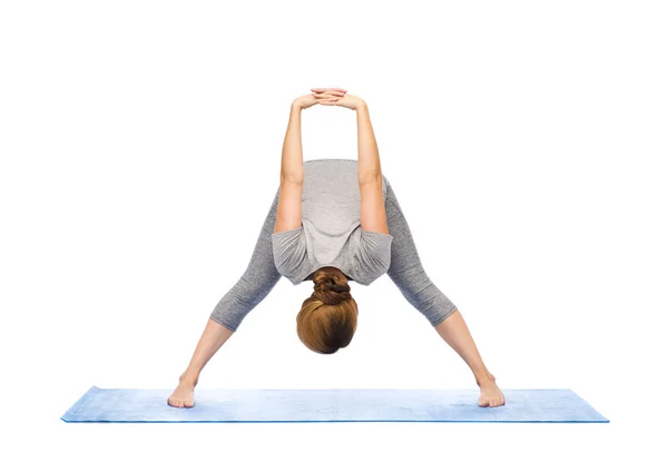 Vrouw maken yoga wide-legged forward bend op mat — Stockfoto