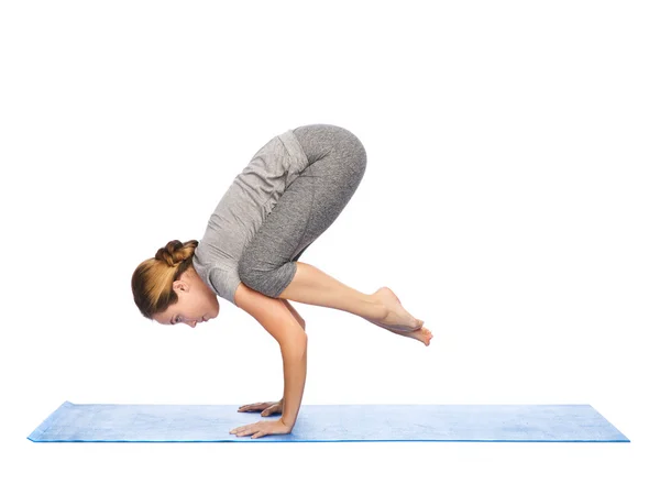 Donna che fa yoga in posa gru sul tappeto — Foto Stock
