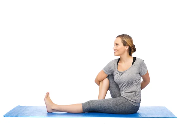 Жінка робить йогу в крученій позі на килимку — стокове фото