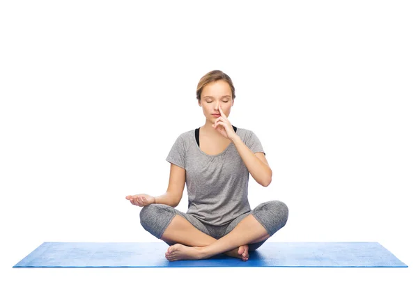 Женщина делает йогу медитации в позе лотоса на мат — стоковое фото