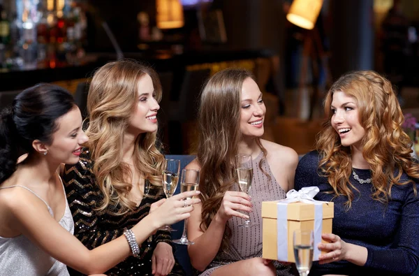 Mulheres felizes com champanhe e presente no clube noturno — Fotografia de Stock