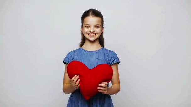 Menina sorridente feliz com travesseiro em forma de coração vermelho — Vídeo de Stock