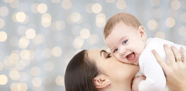 Happy mother kissing her baby over lights — Stok fotoğraf