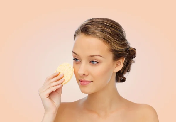 Young woman cleaning face with exfoliating sponge — Stock Photo, Image