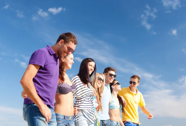 Groep gelukkige vrienden wandelen langs strand — Stockfoto