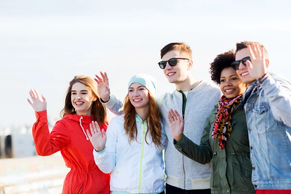 Happy teenage friends waving hands on city street — Stock Photo, Image