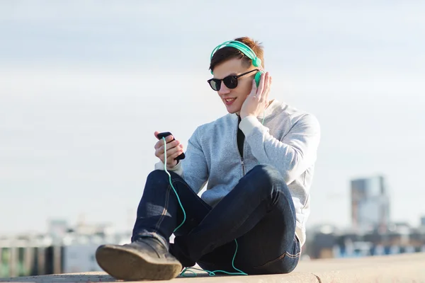 Jovem feliz em fones de ouvido com smartphone — Fotografia de Stock