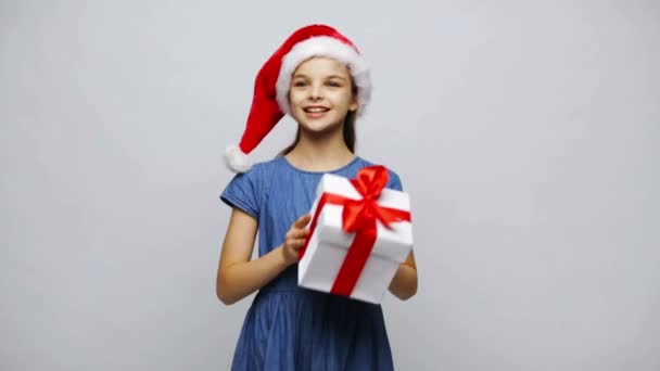Felice sorridente ragazza in cappello di Babbo Natale scuotendo confezione regalo — Video Stock