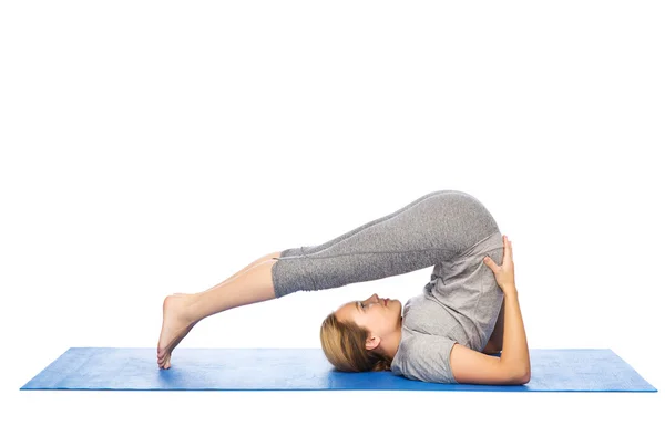 Vrouw maken yoga in ploeg pose op de mat — Stockfoto