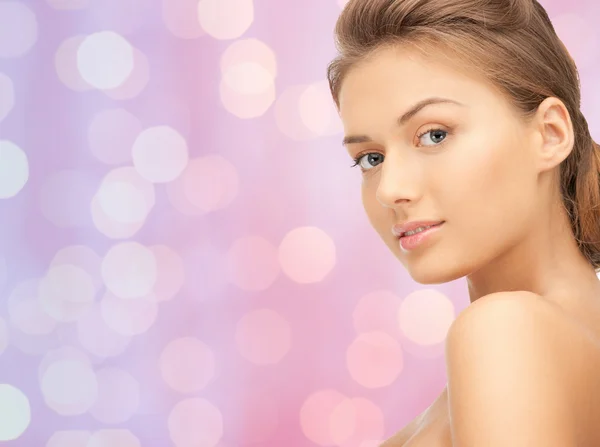 Lovely woman face over pink lights background — Stockfoto