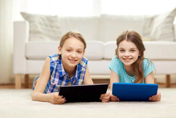 Meninas felizes com tablet pc deitado no chão em casa — Fotografia de Stock