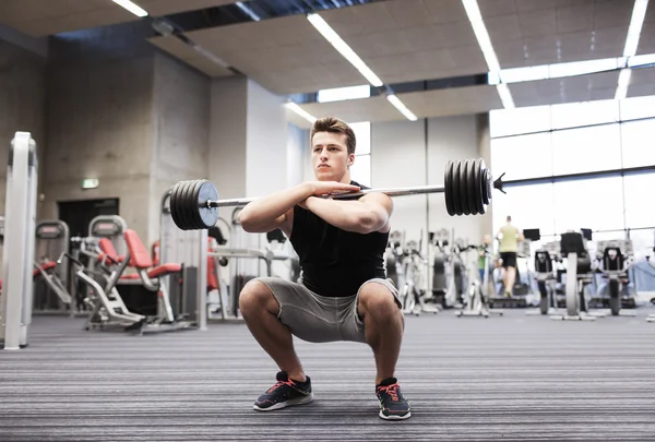 Ung man böjande muskler med skivstång i gymmet — Stockfoto