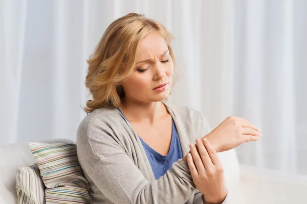Unhappy woman suffering from pain in hand at home — Stock Photo, Image