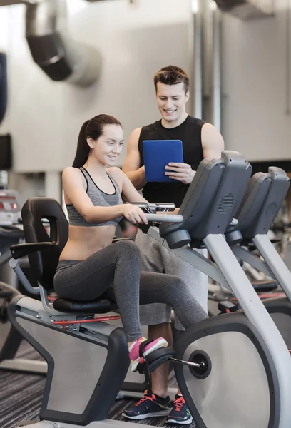 Happy woman with trainer on exercise bike in gym — Stock Photo, Image