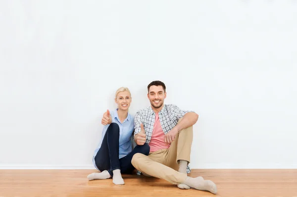 Casal feliz mostrando polegares para cima em nova casa — Fotografia de Stock