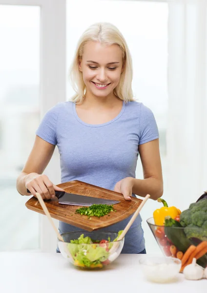 Mujer sonriente cocinando ensalada de verduras en casa —  Fotos de Stock