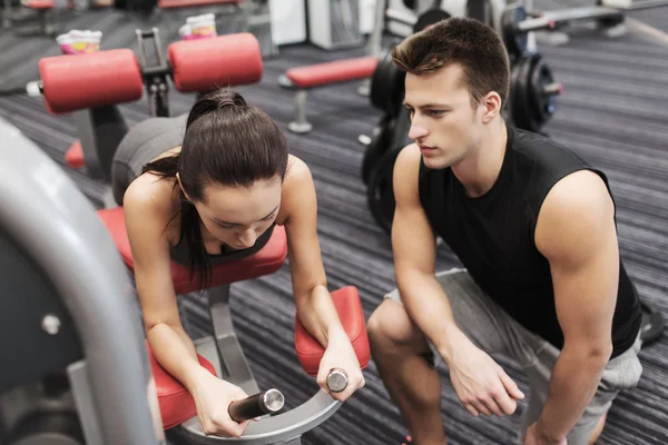 Mujer joven con entrenador haciendo ejercicio en la máquina de gimnasio —  Fotos de Stock