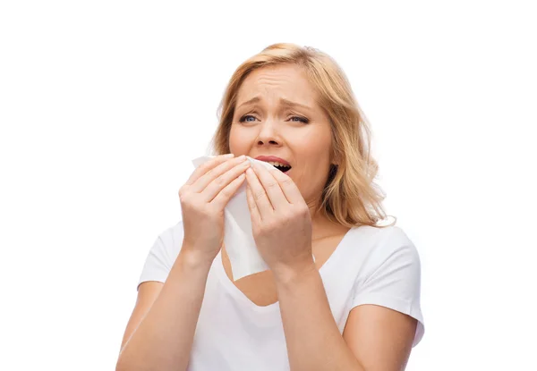 Unhappy woman with paper napkin sneezing — Stock fotografie