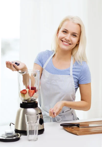 Mulher sorridente com liquidificador preparando shake em casa — Fotografia de Stock