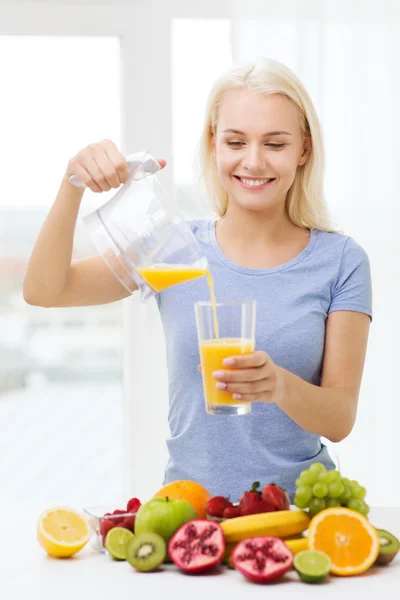 Smiling woman pouring fruit juice to glass at home — 图库照片