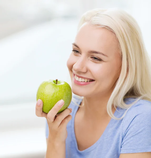 Mulher feliz comer maçã verde em casa — Fotografia de Stock