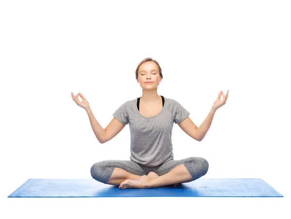 Kvinna att göra yoga meditation i lotus pose på matta — Stockfoto