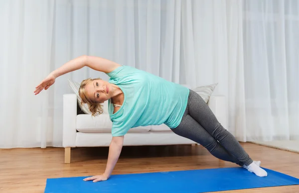 Mujer haciendo ejercicio en la esterilla en casa — Foto de Stock