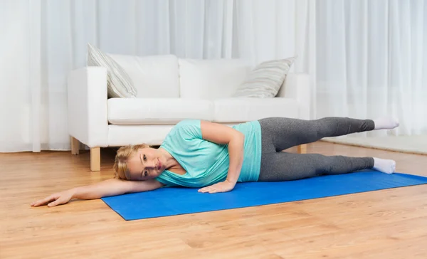 Mujer haciendo ejercicio en la esterilla en casa — Foto de Stock