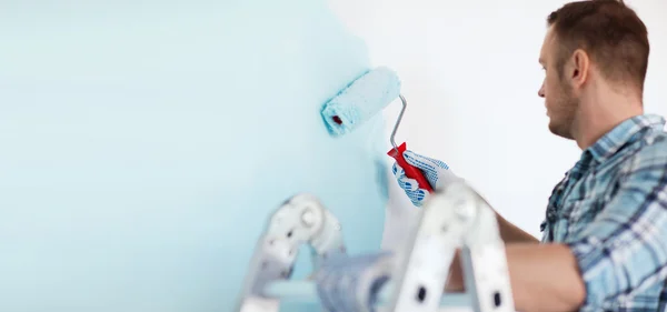 Close up de macho em luvas segurando rolo de pintura — Fotografia de Stock