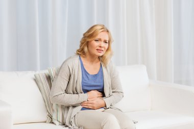 unhappy woman suffering from stomach ache at home clipart