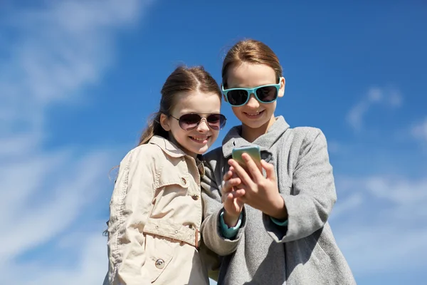 Счастливые девушки со смартфоном делают селфи на открытом воздухе — стоковое фото