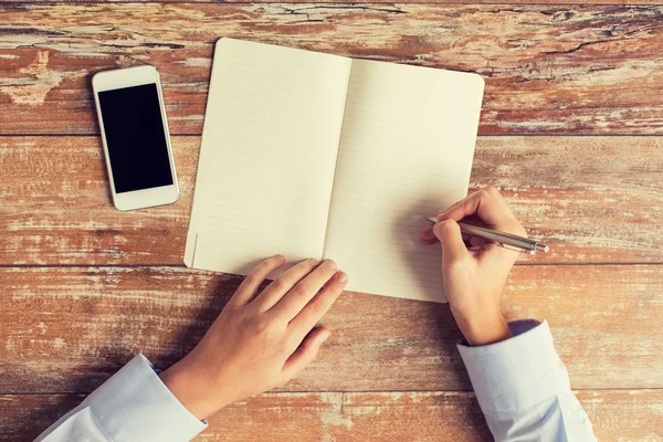 Närbild på händerna med anteckningsboken och smartphone — Stockfoto