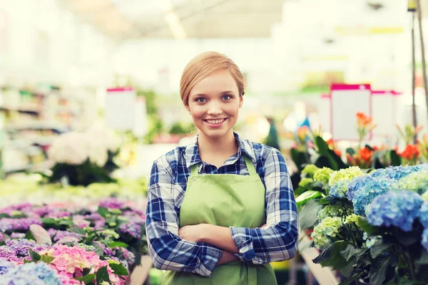 Glad kvinna med blommor i växthus Stockfoto