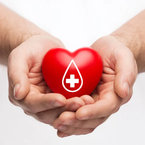 Mani maschili che tengono il cuore rosso con segno del donatore — Foto Stock