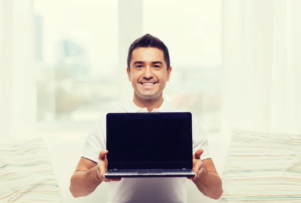 Homem feliz mostrando tela em branco laptop em casa — Fotografia de Stock