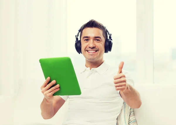 Hombre sonriente con tablet PC y auriculares en casa — Foto de Stock