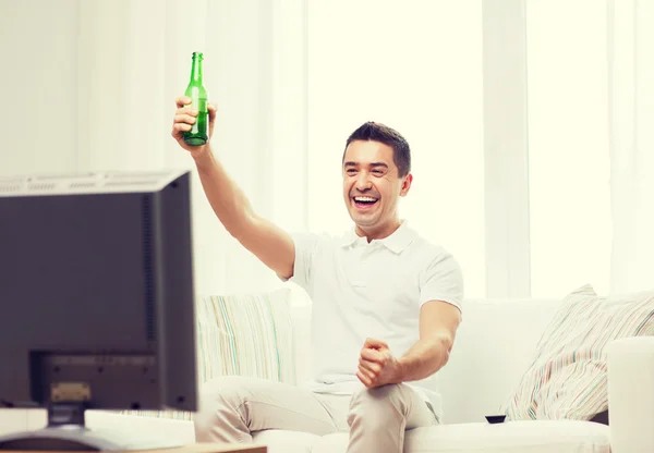 Glimlachende man tv kijken en thuis bier drinken — Stockfoto