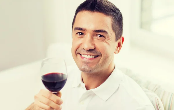 Homem feliz bebendo vinho tinto de vidro em casa — Fotografia de Stock