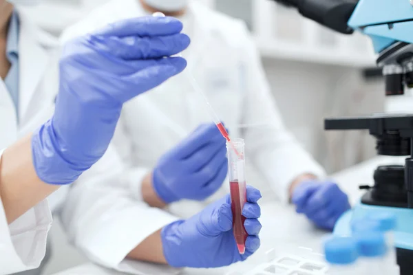 Perto de cientistas que enchem o tubo de ensaio no laboratório — Fotografia de Stock