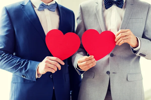 Close up of male gay couple holding red hearts — Stock Photo, Image