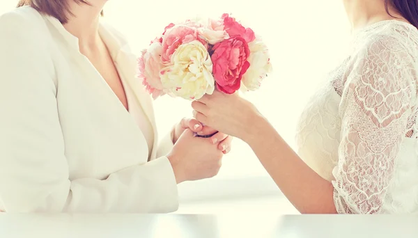 Close up of happy lesbian couple with flowers — Stock Photo, Image