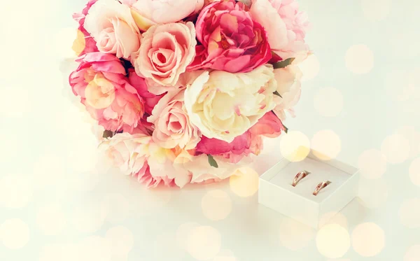 Primer plano de dos anillos de boda y ramo de flores — Foto de Stock
